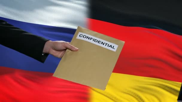 Rússia e Alemanha funcionários trocando envelope confidencial, bandeiras de fundo — Vídeo de Stock
