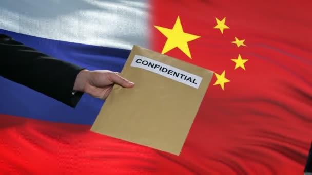 Rússia e China funcionários trocando envelope confidencial, bandeiras de fundo — Vídeo de Stock