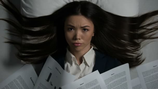 Jonge Aziatische vrouw bedekt met stapel documenten verdwijnende op bed, overwerk — Stockvideo