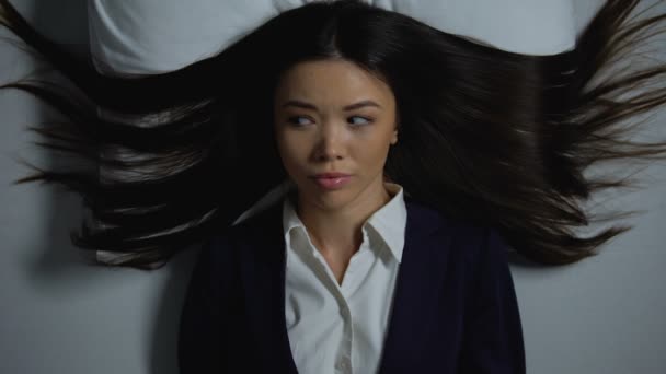 Aziatische vrouw in Business pak liggend in bed, lijden paranoia van overwerk — Stockvideo