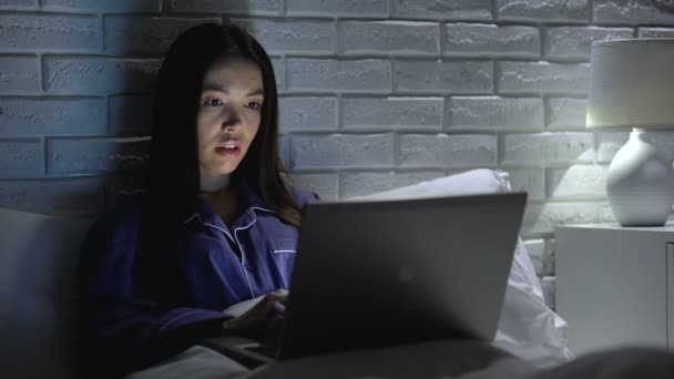 Donna sdraiata a letto che lavora frettolosamente sul computer portatile, cercando di rispettare la scadenza, ore di lavoro straordinario — Video Stock