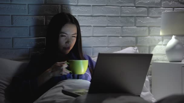 亚洲妇女喝咖啡工作在笔记本电脑在卧室后期,满足最后期限 — 图库视频影像