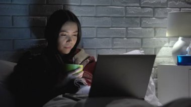 Kız yatakta yatarken, çay içmekten, dizüstü bilgisayarda film izlerken, grip sezonunda kendini hasta hissediyor.