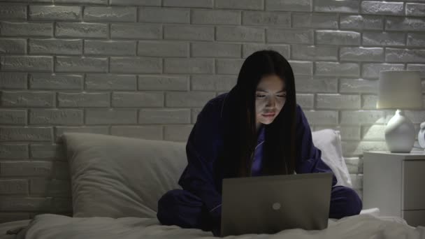 疲惫的女人按摩颈部,坐在床上不舒服,当在笔记本电脑上工作 — 图库视频影像