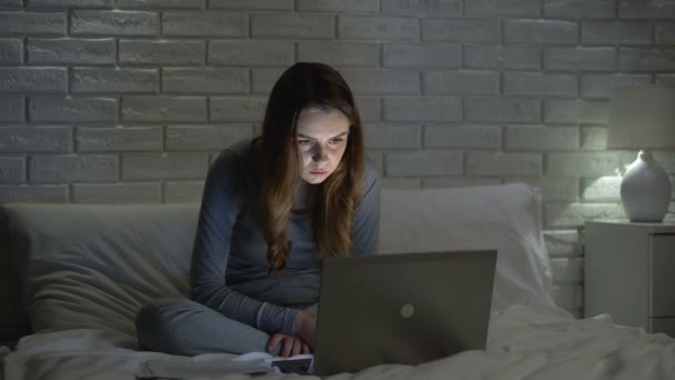 Бліда дівчина, використовуючи Інтернет пізно вночі, виглядає виснаженою, залежною від мереж — стокове відео