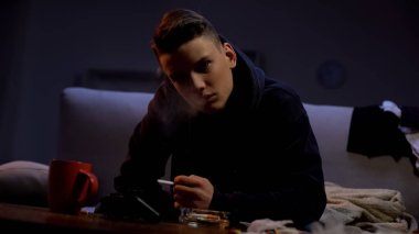 Asi genç sigara ve kamera bakarak, garip yaş sorunu