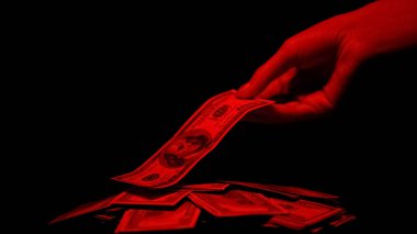 Hand taking dollar from pile illuminated by red light, bloody money crime reward clipart