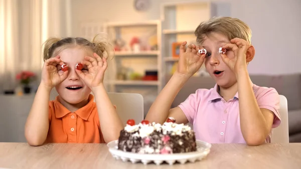 Alegre Hermano Hermana Sosteniendo Pastel Cerezas Frente Los Ojos Jugando —  Fotos de Stock