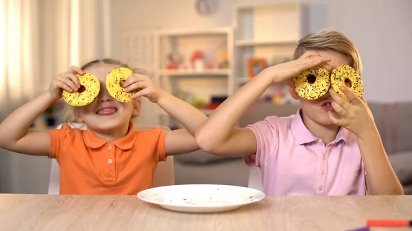 Menina Menino Segurando Donuts Amarelos Frente Dos Olhos Divertindo Lanche — Fotografia de Stock