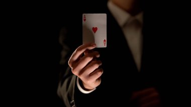 Kamera, sihirli hile, siyah arka plan kalp kartı as gösteren Illusionist