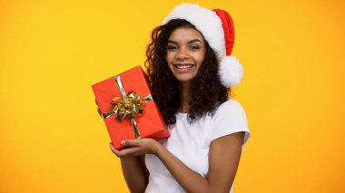 Kırmızı hediye kutusu tutan ve gülümseyen Noel Baba şapka neşeli çekici kadın