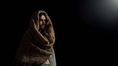 İsa cüppe karanlıkta ayakta, günahkar dünyada kurtuluş için umut olarak din