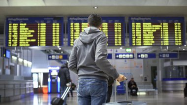 Tren istasyonunda ki zaman tablosuna bakan, kalkışa hazırlanan adam yolcusu