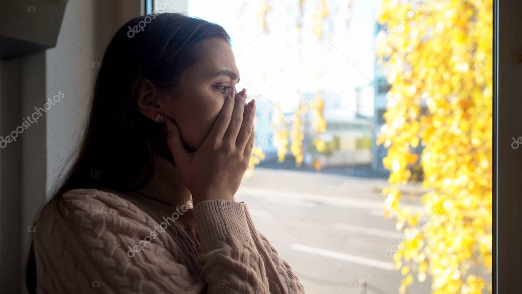 Crying lady looking through window, afraid of going outdoors agoraphobia disease