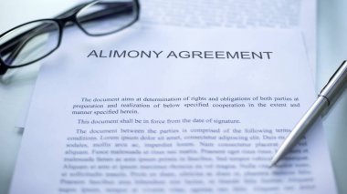 Alimony agreement lying on table, pen and eyeglasses on official document clipart