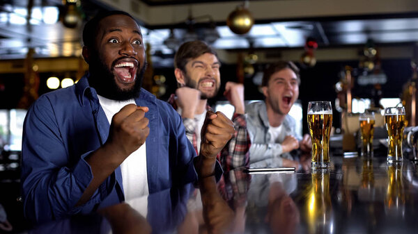 Emotional african-american male celebrating favorite team victory, rest in bar