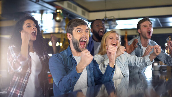 Extremely happy sport fans actively cheering team, celebrating victory in bar