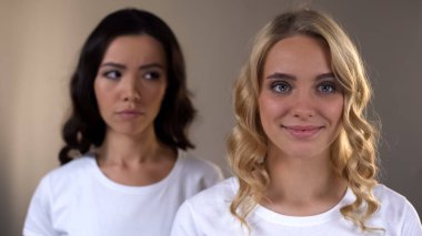 Aynaya bakan güzel sarışın kadın, arka planda kıskanç kadın arkadaş