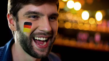 Yanak üzerinde bayrak ile Neşeli Alman fan bağırarak ve zafer kutluyor, hedef