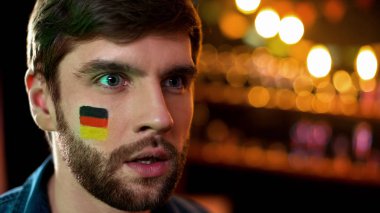 Yanak boyalı alman bayrağı ile mutsuz erkek tv izlerken, takım oyunu kaybetme