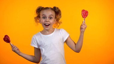 Güzel kız iki kalp şeklinde lolipop tutan, cam gülümseyen ve eğlenmek