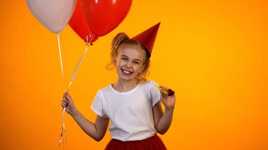 Hava balonları ve parti üfleyici kameraya gülümseyen sevimli kız, kutlama