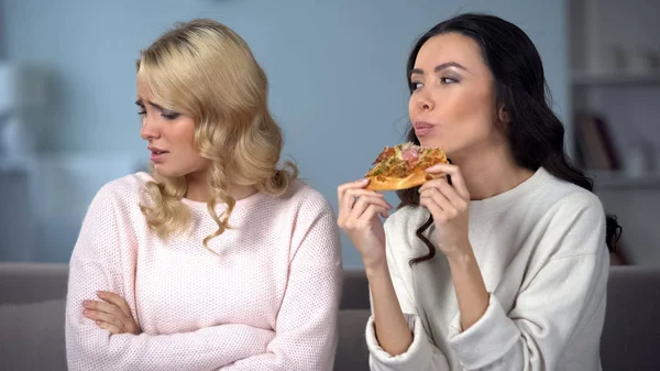 妇女吃开胃比萨饼 而朋友战斗与快餐吃欲望 — 图库照片