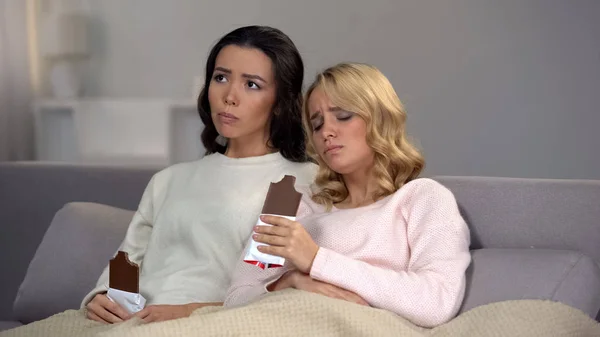 Två Upprörda Kvinnliga Vänner Som Äter Choklad Lider Premenstruella Syndrom — Stockfoto
