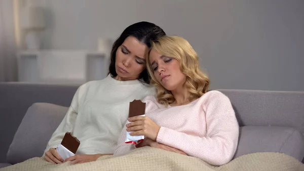 两个心烦意乱的女性朋友吃巧克力 支持后关系刹车 — 图库照片