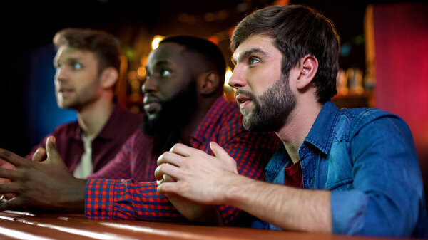 Nervous multiracial friends watching auto racing supporting favourite driver