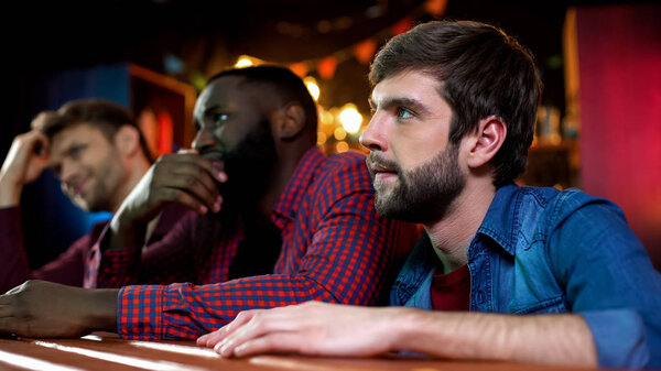 Football fans watching game in pub, male friends disappointed with team lose