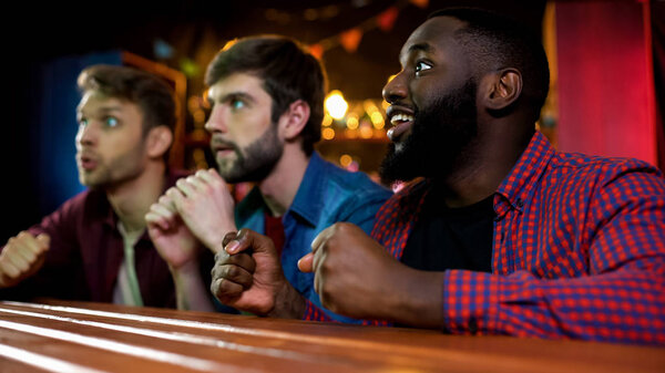 Three multiethnic friends waiting for match result, hoping for team victory