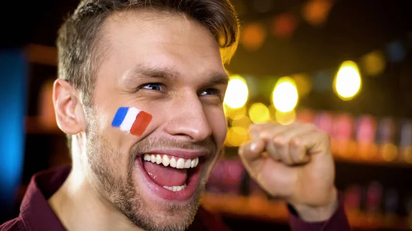 チームの勝利を祝う塗装された旗を持つ喜びに満ちたフランスのファンは はいジェスチャーを作ります — ストック写真