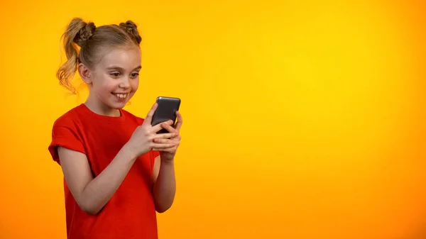 快乐青春期前的女孩滚动智能手机和微笑 教育应用程序 小工具 — 图库照片