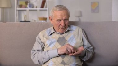 Üzgün yaşlı adam kanepede oturan ve avuç içi para sayma, sosyal güvensizlik