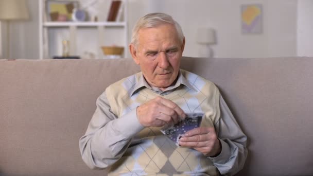 Homem idoso perturbado sentado no sofá, segurando notas de euro, insegurança social — Vídeo de Stock
