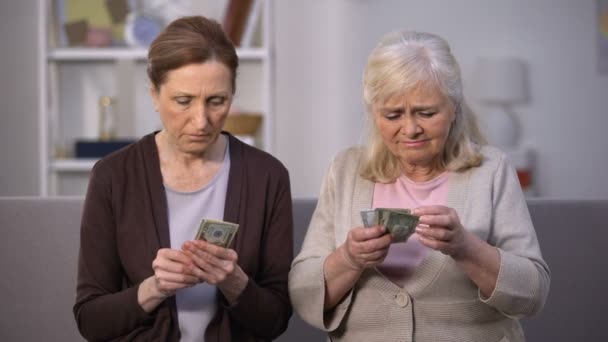 Amigos idosas perturbadas segurando notas de dólares, sofrendo de pobreza — Vídeo de Stock