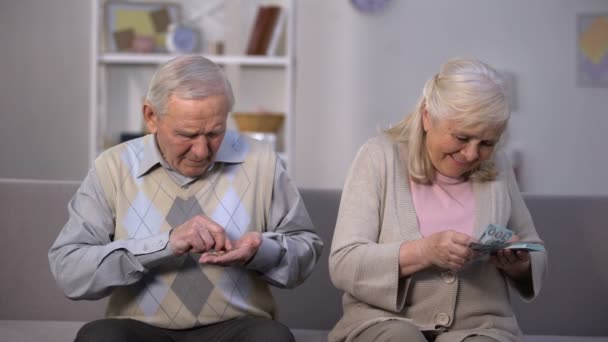 Hombre viejo contando monedas mirando a la mujer mayor feliz calculando dólares, riqueza — Vídeo de stock