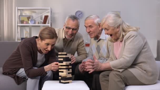 Пожилые друзья строят башню из деревянных кубиков досуга в доме престарелых — стоковое видео