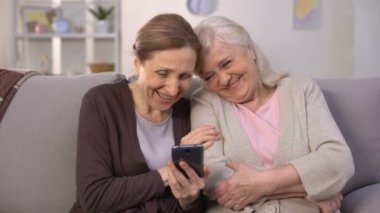 Neşeli yaşlı kadınlar akıllı telefon ve gülerek, iyi anılar fotoğrafları izlerken