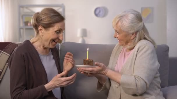 Donna matura che presenta la torta di compleanno a sua sorella, felice signora che soffia candela — Video Stock