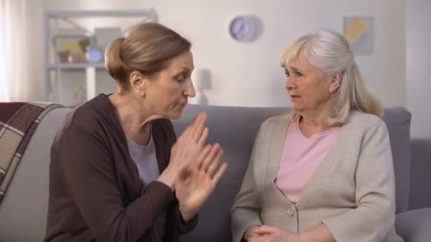 Self-assertive old women arguing and offending each other sitting in living room — Stock Video