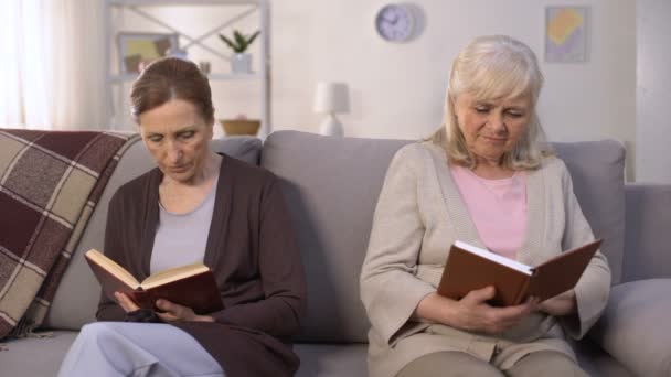 Zwei neidische alte Frauen, die Bücher lesen, sitzen auf dem Flur des Pflegeheims, Rivalität — Stockvideo