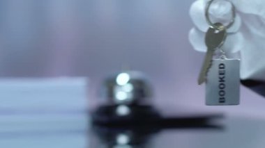 Anahtarlık üzerine rezervasyonlu kelime, kadın müşteriye anahtar veren erkek yönetici, closeup