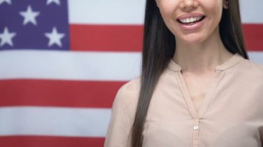 Amerikan bayrağı arka plan, göç üzerinde yakın çekim kadar başparmak gösteren neşeli kadın