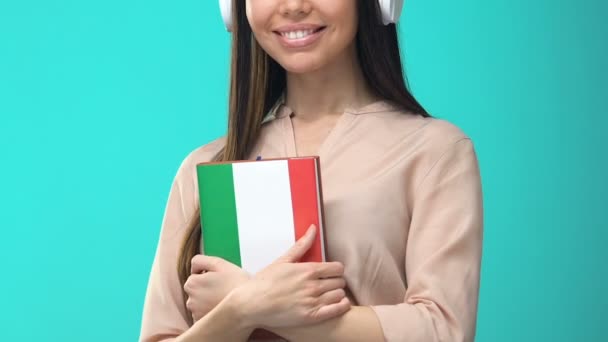Felizes fones de ouvido estudante segurando livro italiano, seminário on-line, conhecimento — Vídeo de Stock
