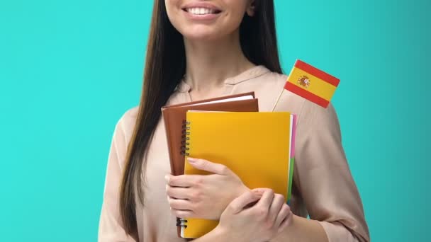 Örömteli fiatal nő, aki spanyol zászlós noteszgépekkel, nemzetközi oktatással