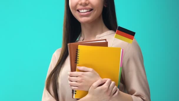 Χαρούμενη νεαρή γυναίκα που κρατά σημειωματάρια γερμανικής σημαίας στα χέρια, μαγεία στο εξωτερικό — Αρχείο Βίντεο