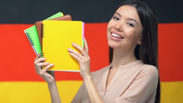 Happy student visar anteckningsböcker tyska flaggan bakgrund, undervisning på universitetet — Stockvideo