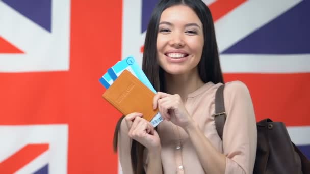 Mujer feliz mostrando boletos y pasaporte, bandera inglesa, viajando a Gran Bretaña — Vídeos de Stock